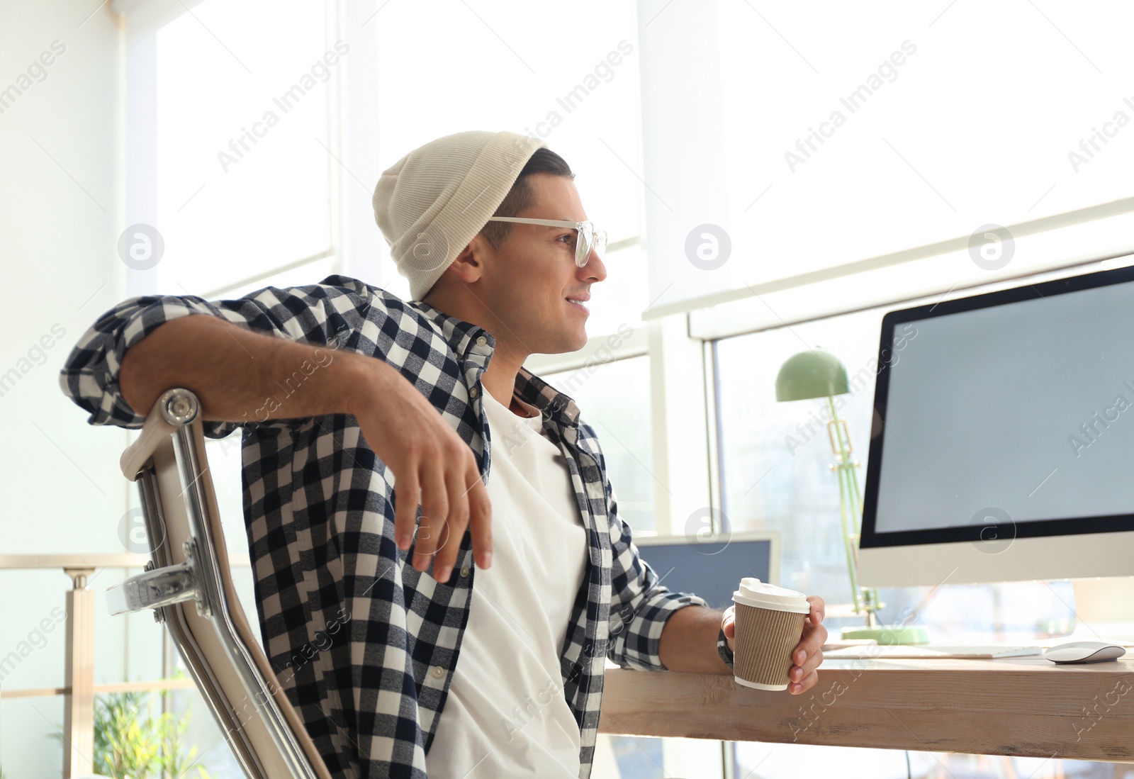 Photo of Freelancer with cup of coffee working on computer at table indoors