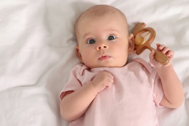 Photo of Cute little baby with toy on white sheets, top view