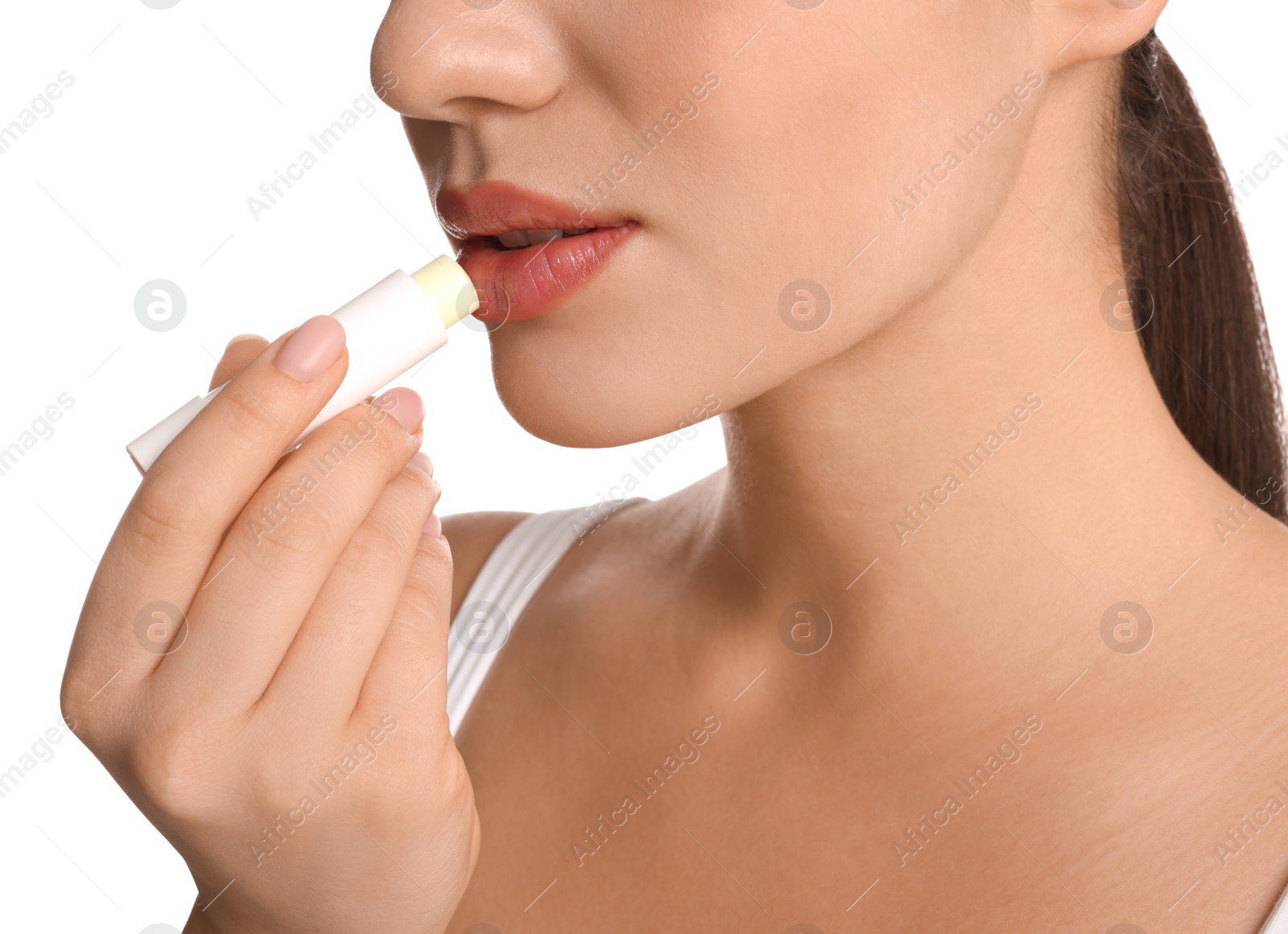 Photo of Young woman applying lip balm on white background, closeup