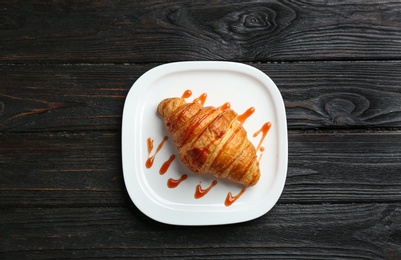 Plate of tasty croissant with jam on dark wooden background, top view. French pastry