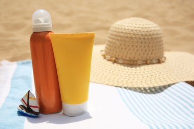 Sunscreens and beach accessories on sand, space for text. Sun protection care