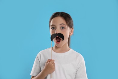 Photo of Cute little girl with fake mustache on turquoise background