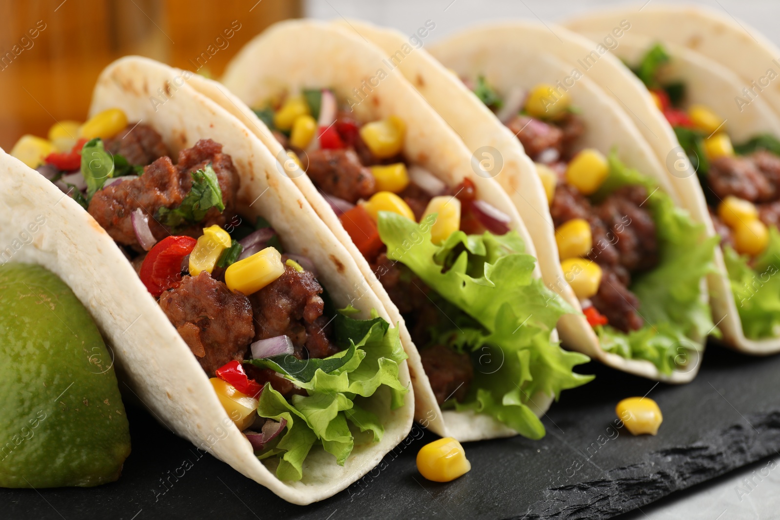 Photo of Delicious tacos with meat and vegetables on table, closeup