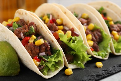 Photo of Delicious tacos with meat and vegetables on table, closeup