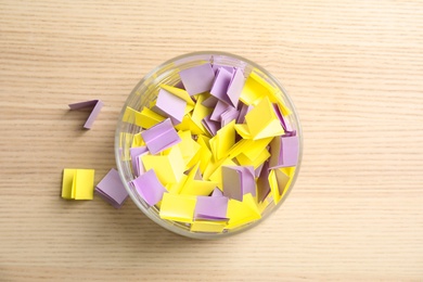 Photo of Colorful paper pieces for lottery in glass vase on wooden background, top view