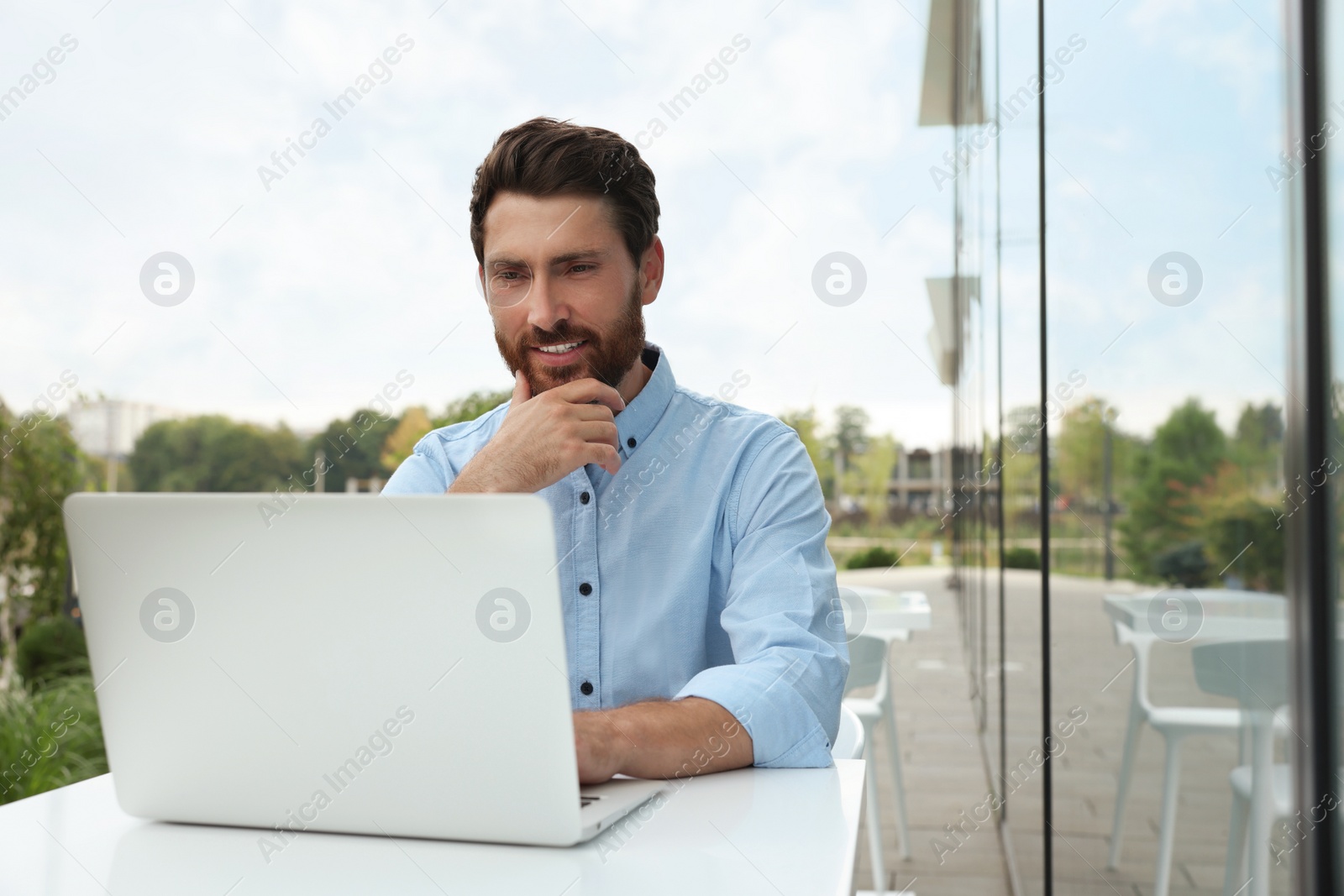 Photo of Handsome man with laptop in outdoor cafe