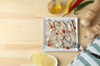 Photo of Tasty pickled anchovies served on wooden table, flat lay. Space for text