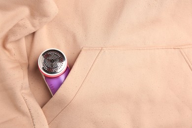 Photo of Fabric shaver in pocket of beige sweatshirt with lint, top view