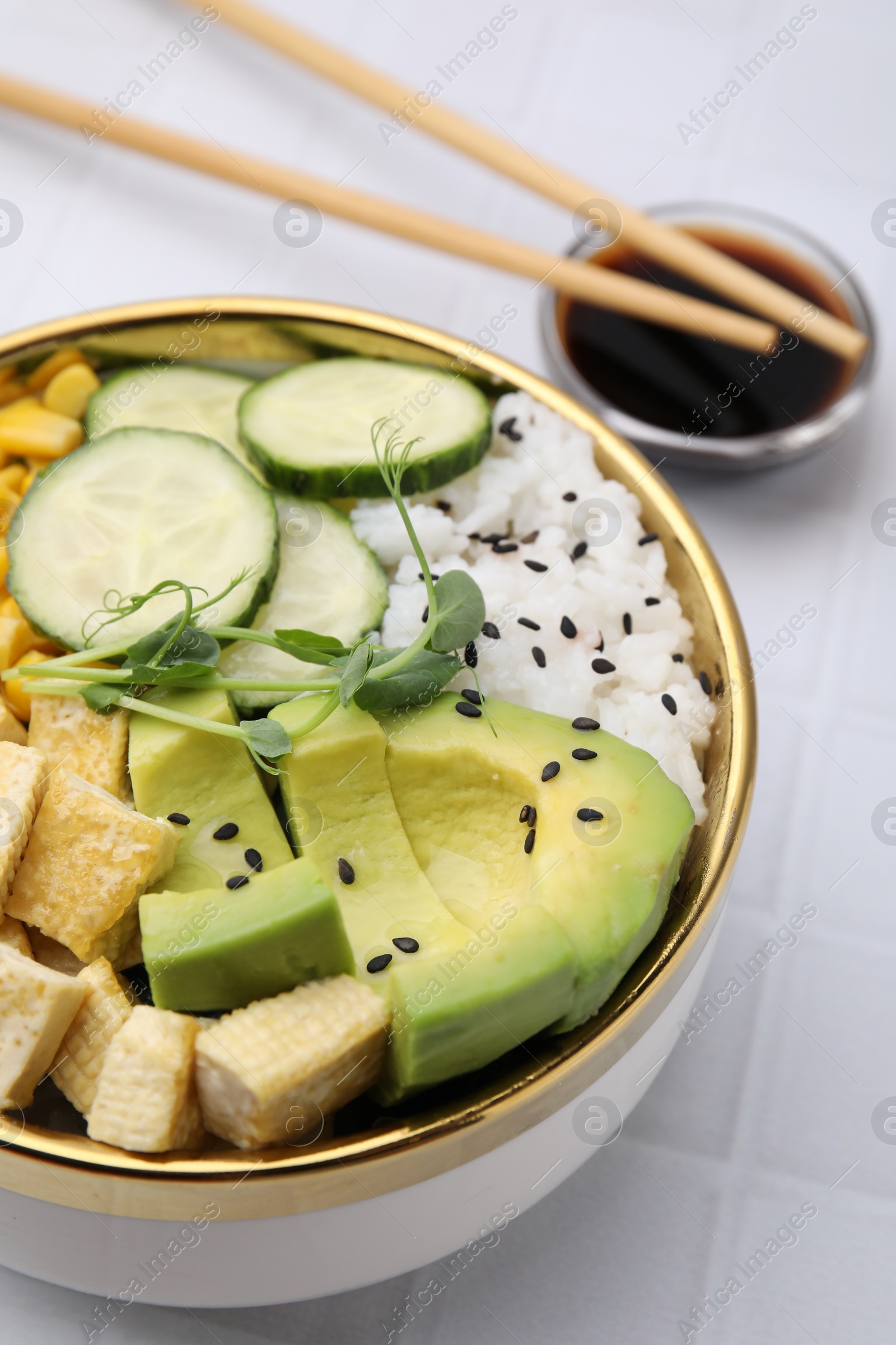 Photo of Delicious poke bowl with vegetables, tofu, avocado and microgreens served on white tiled table, closeup