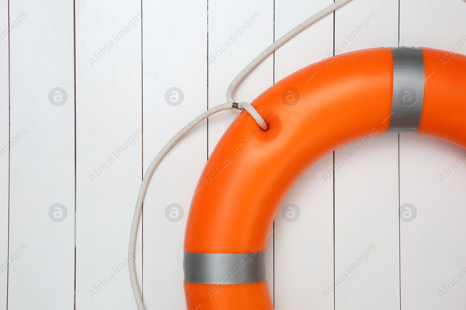 Photo of Orange lifebuoy on white wooden background, space for text. Rescue equipment