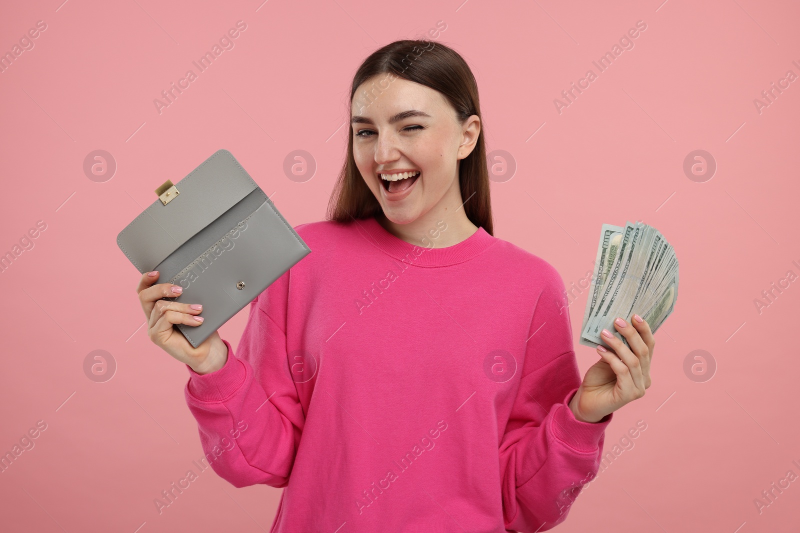 Photo of Happy woman with wallet and dollar banknotes on pink background