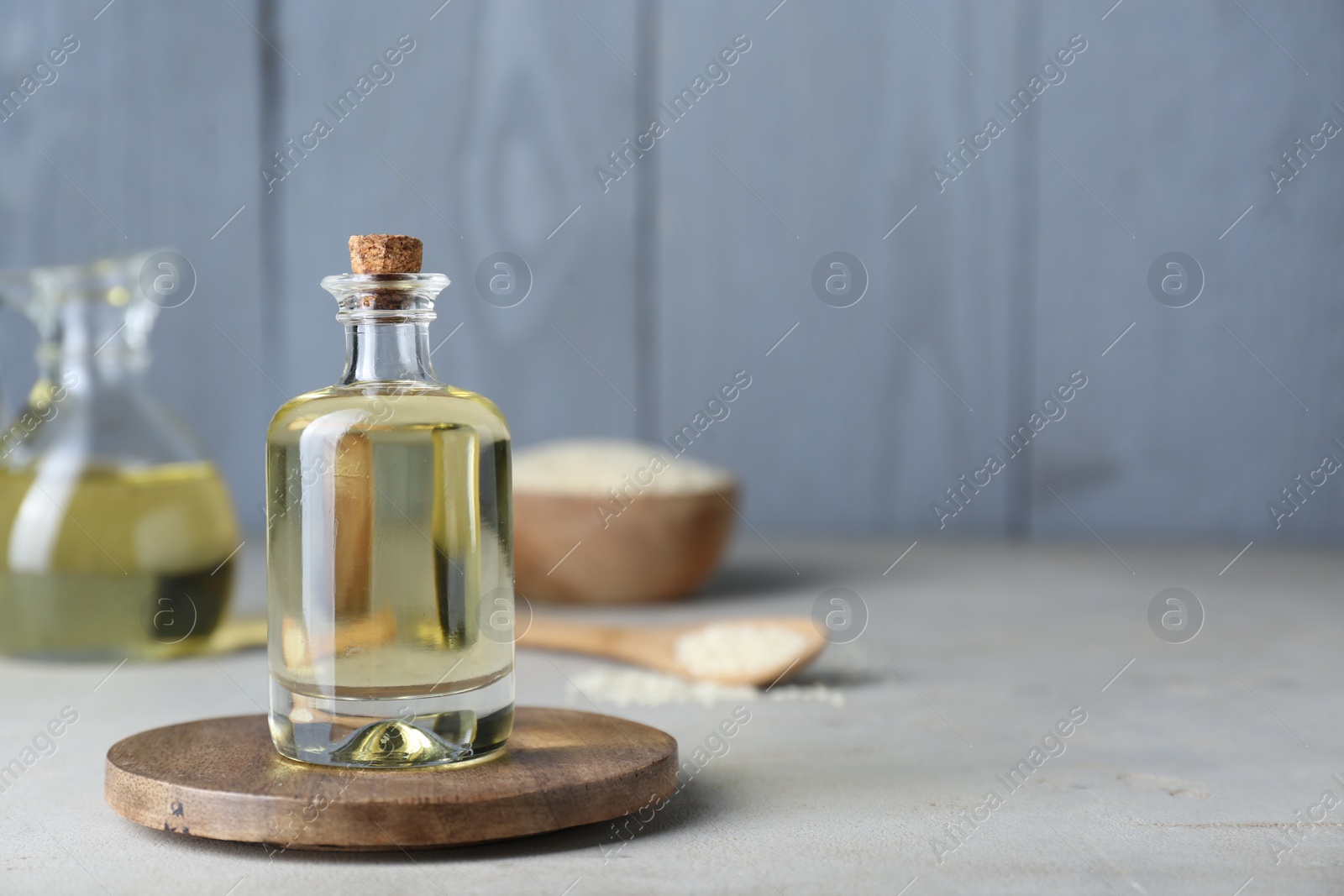 Photo of Sesame oil in glass bottle on light grey table. Space for text