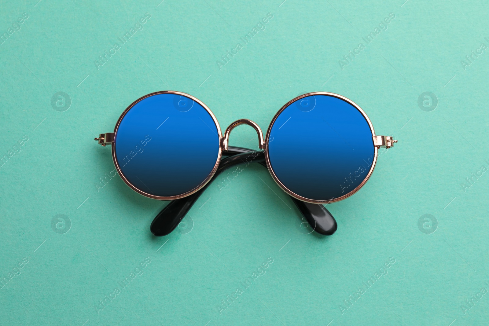 Photo of New stylish elegant sunglasses on turquoise background, top view