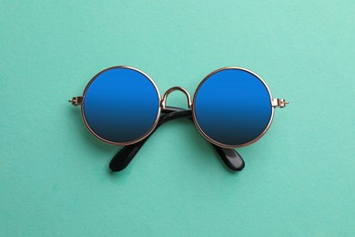 Photo of New stylish elegant sunglasses on turquoise background, top view