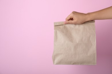 Photo of Woman holding paper bag on pink background, closeup. Space for text