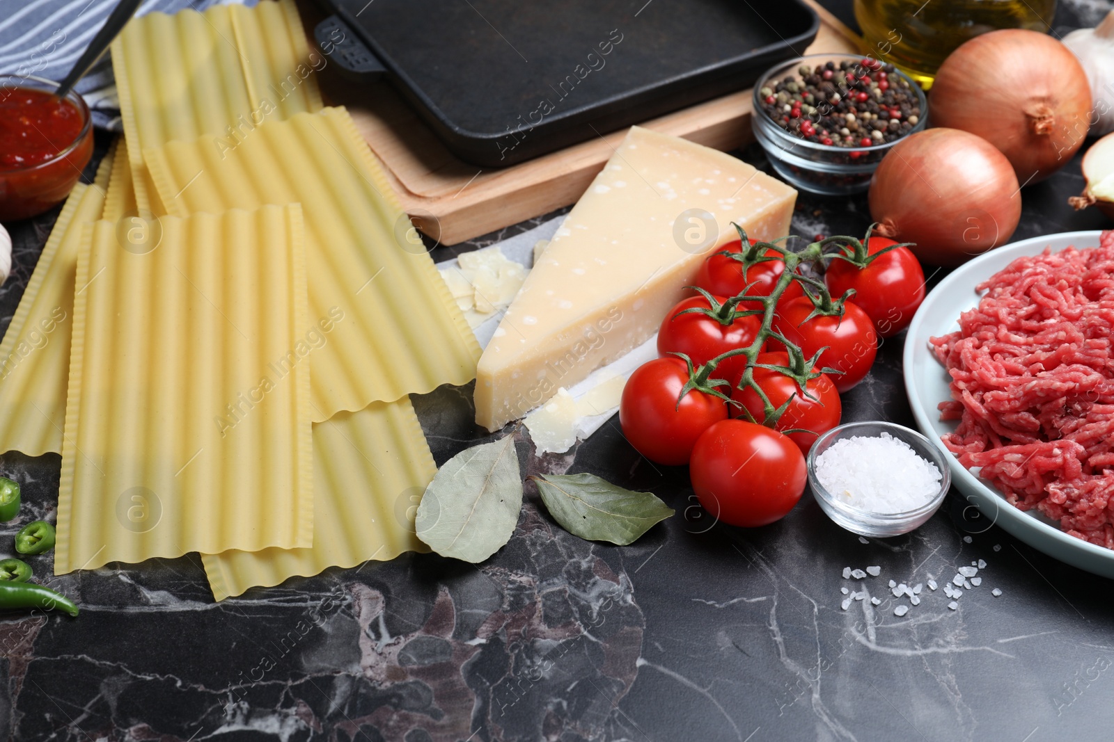 Photo of Fresh ingredients for lasagna on black marble table