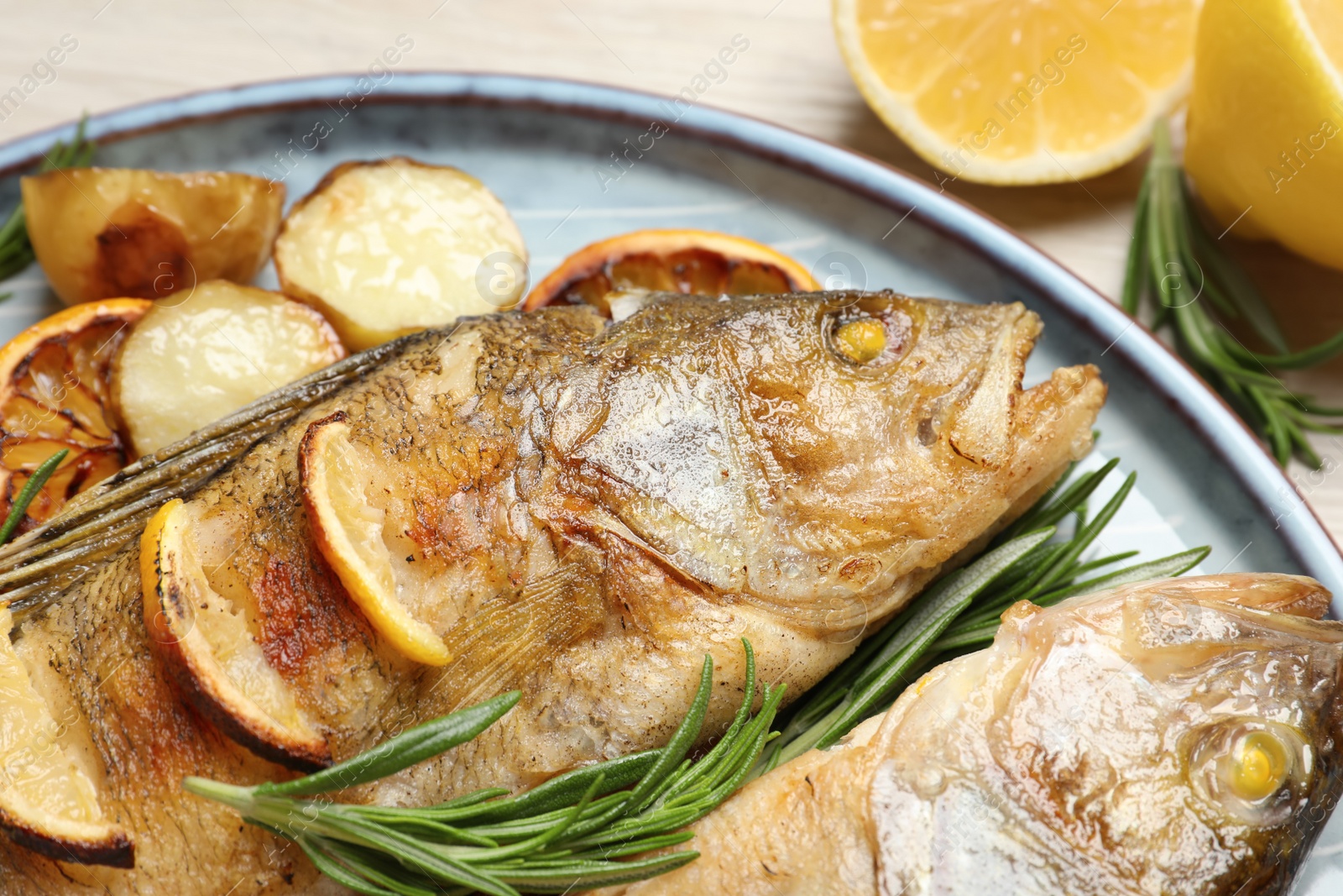 Photo of Tasty homemade roasted perches served on table, closeup. River fish