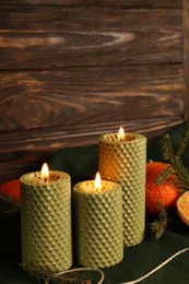 Photo of Beautiful burning beeswax candles, rope and tangerines on table