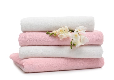 Stack of clean folded towels with flowers on white background