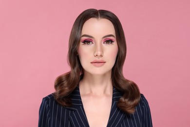 Photo of Portrait of beautiful young woman with makeup and gorgeous hair styling on pink background