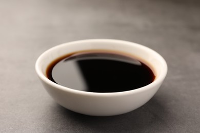 Bowl of soy sauce on grey table, closeup