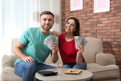 Beautiful young couple with money at home