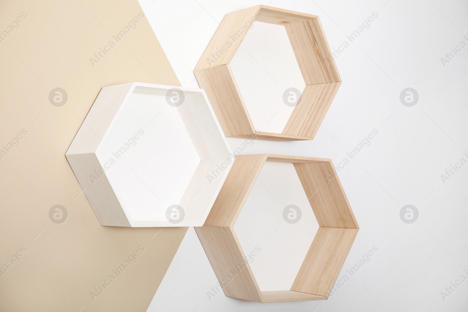 Photo of Empty honeycomb shaped shelves on color wall