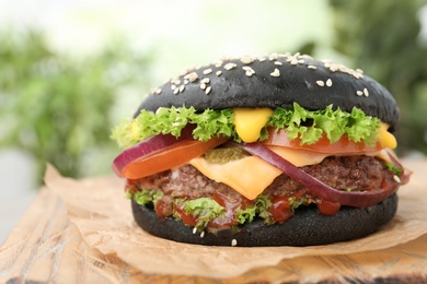 Photo of Board with black burger on blurred background, closeup