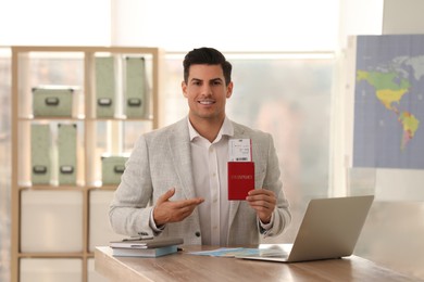 Travel agent with ticket and passport in office