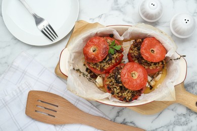 Baking dish of delicious stuffed tomatoes with minced beef, bulgur and mushrooms on white marble table, flat lay