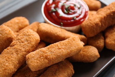 Photo of Plate of tasty crispy cheese sticks with sauce, closeup