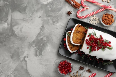 Photo of Traditional classic Christmas cake decorated with cranberries, pomegranate seeds and rosemary on grey table, flat lay. Space for text
