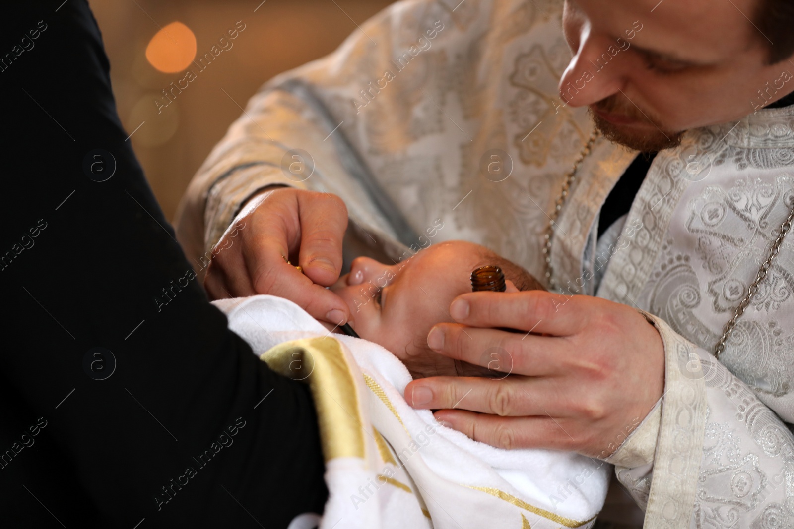 Photo of MYKOLAIV, UKRAINE - FEBRUARY 27, 2021: Man holding baby in Kasperovskaya icon of Mother of God cathedral during baptism ceremony, closeup