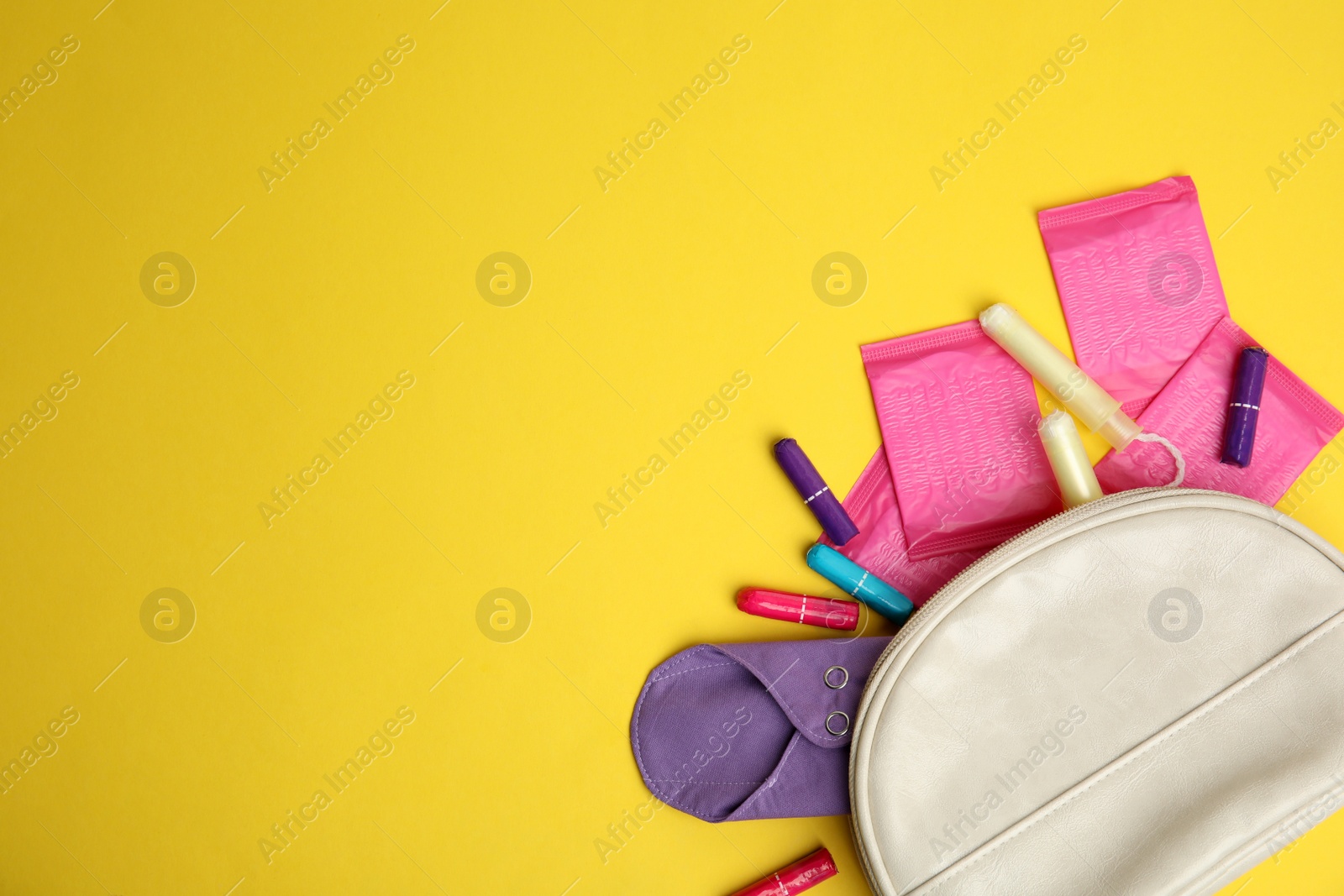 Photo of Tampons and other menstrual hygienic products on yellow background, flat lay. Space for text