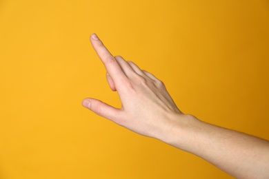 Photo of Woman pointing at something on yellow background, closeup. Finger gesture