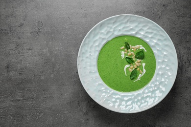 Plate of healthy green soup with fresh spinach on grey table, top view. Space for text