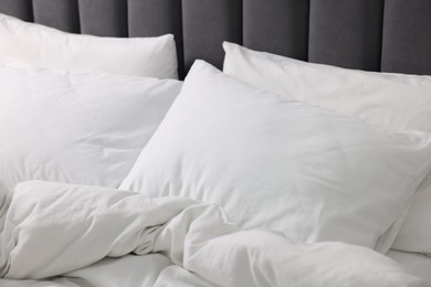 Photo of Soft white pillows and duvet on bed