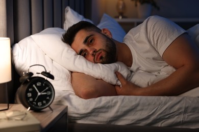 Frustrated man suffering from insomnia on bed