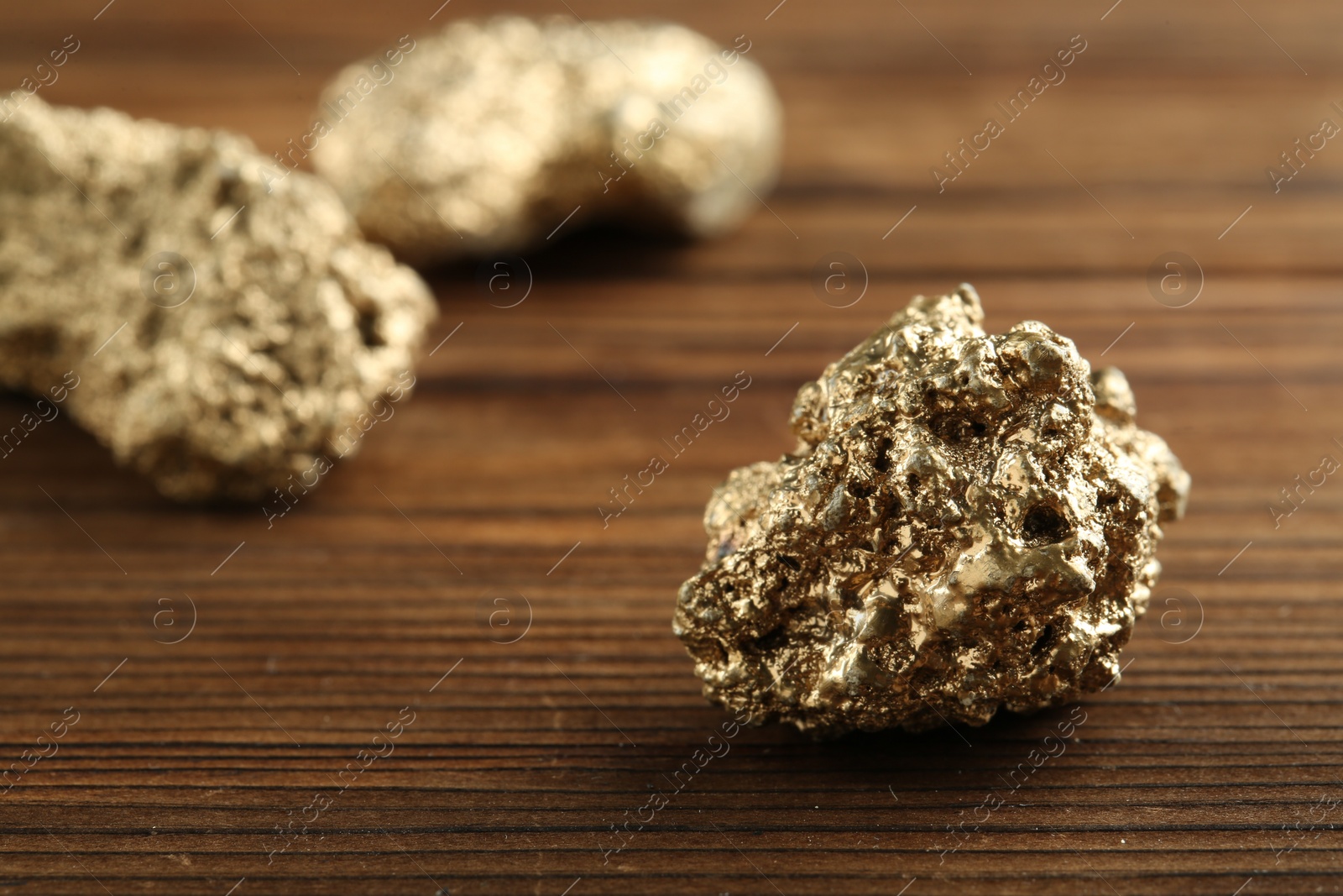 Photo of Shiny gold nugget on wooden table, closeup. Space for text
