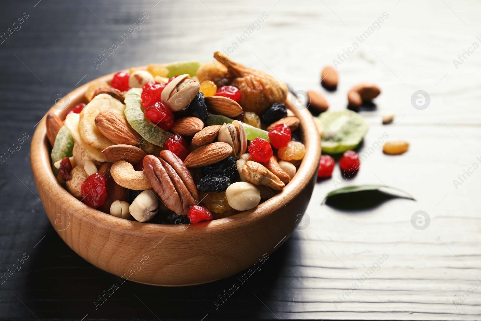 Photo of Bowl of different dried fruits and nuts on table. Space for text