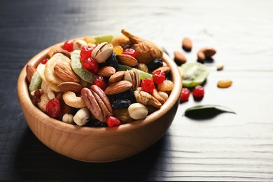Bowl of different dried fruits and nuts on table. Space for text