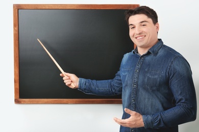 Photo of Portrait of male teacher with pointer near chalkboard in classroom