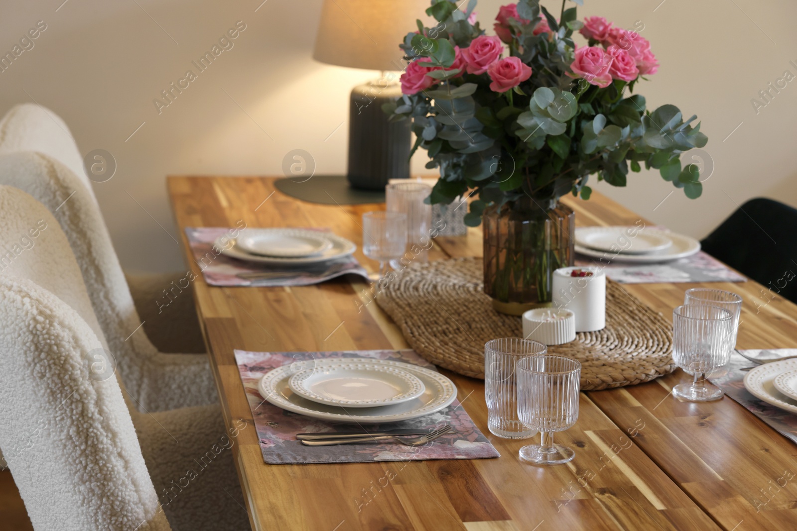 Photo of Beautiful table setting with bouquet and candles indoors. Roses and eucalyptus branches in vase