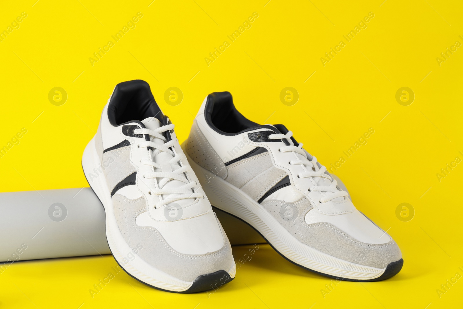 Photo of Pair of stylish sneakers on yellow background