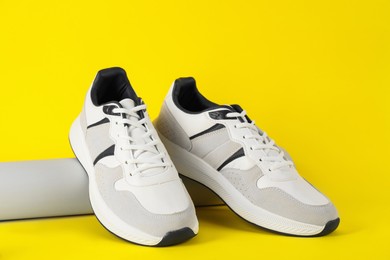 Photo of Pair of stylish sneakers on yellow background