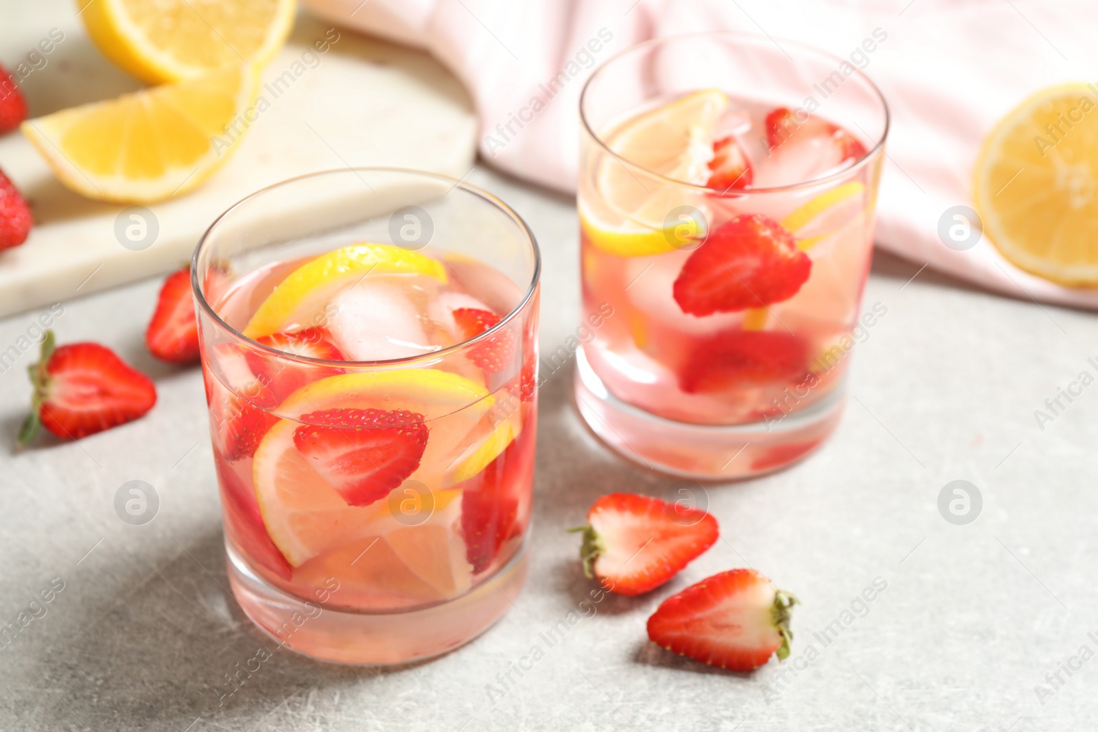 Photo of Tasty refreshing drink with strawberries and lemon on light grey table