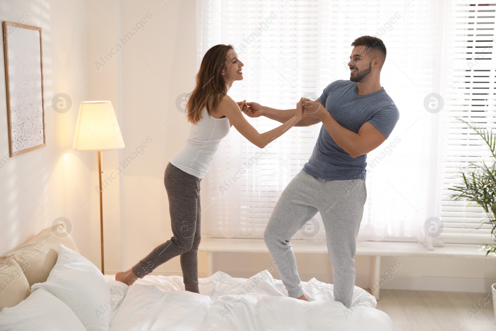 Photo of Lovely young couple dancing on bed at home