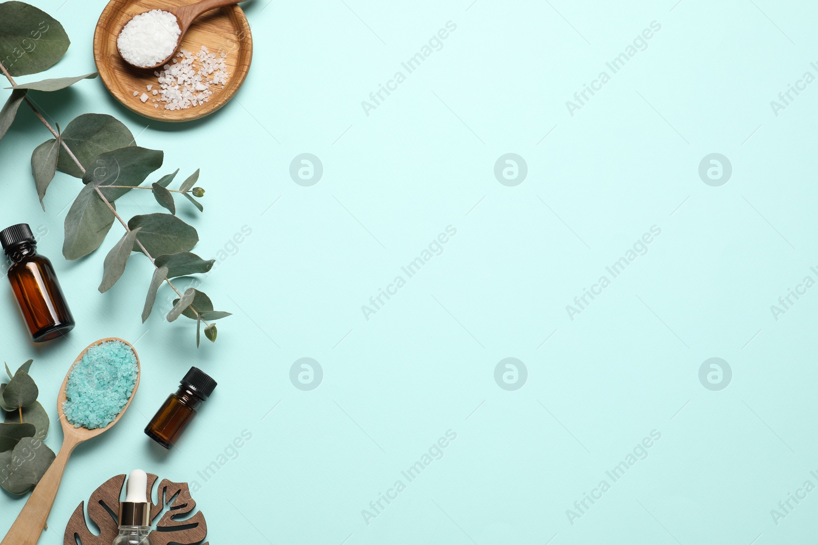 Photo of Aromatherapy products. Bottles of essential oil, sea salt and eucalyptus branches on light blue background, flat lay. Space for text