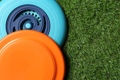 Photo of Plastic frisbee disks on green grass, flat lay. Space for text