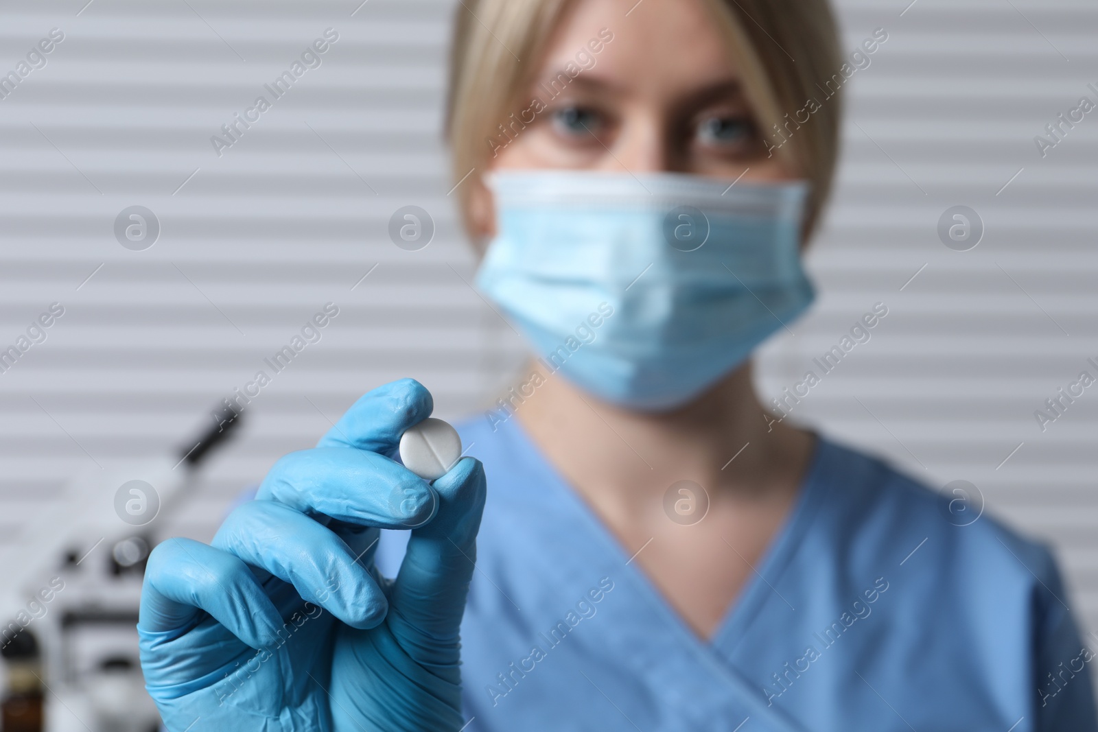 Photo of Doctor holding pill on light background, selective focus. Space for text